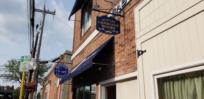 The round Babylon Bean Coffee sign beside the Babylon Carriage House sign
