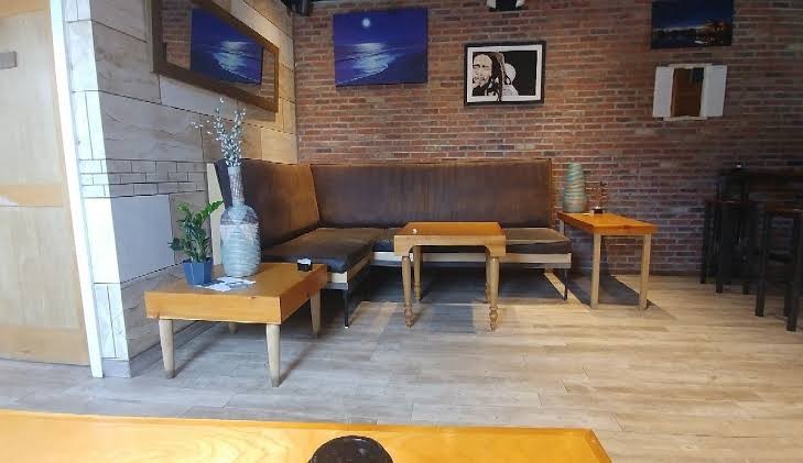 The Bay Shore Bean lounge: a long couch against a brick wall with ocean paintings