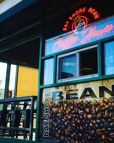 The neon Bay Shore Bean Coffee House sign over a coffee bean mural