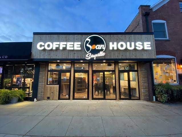 Sayville Bean Coffee House at dusk, its sign lit up over Main Street